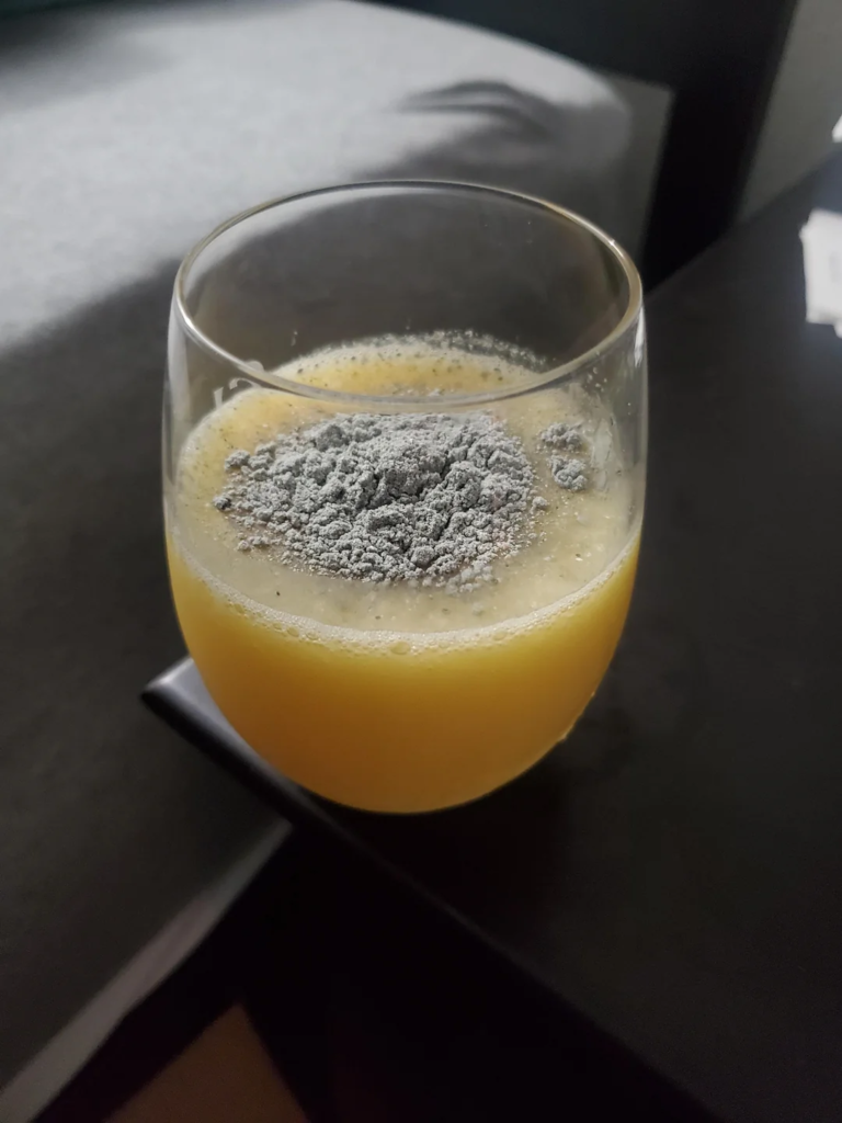 Dried powder shrooms in a glass of orange juice.